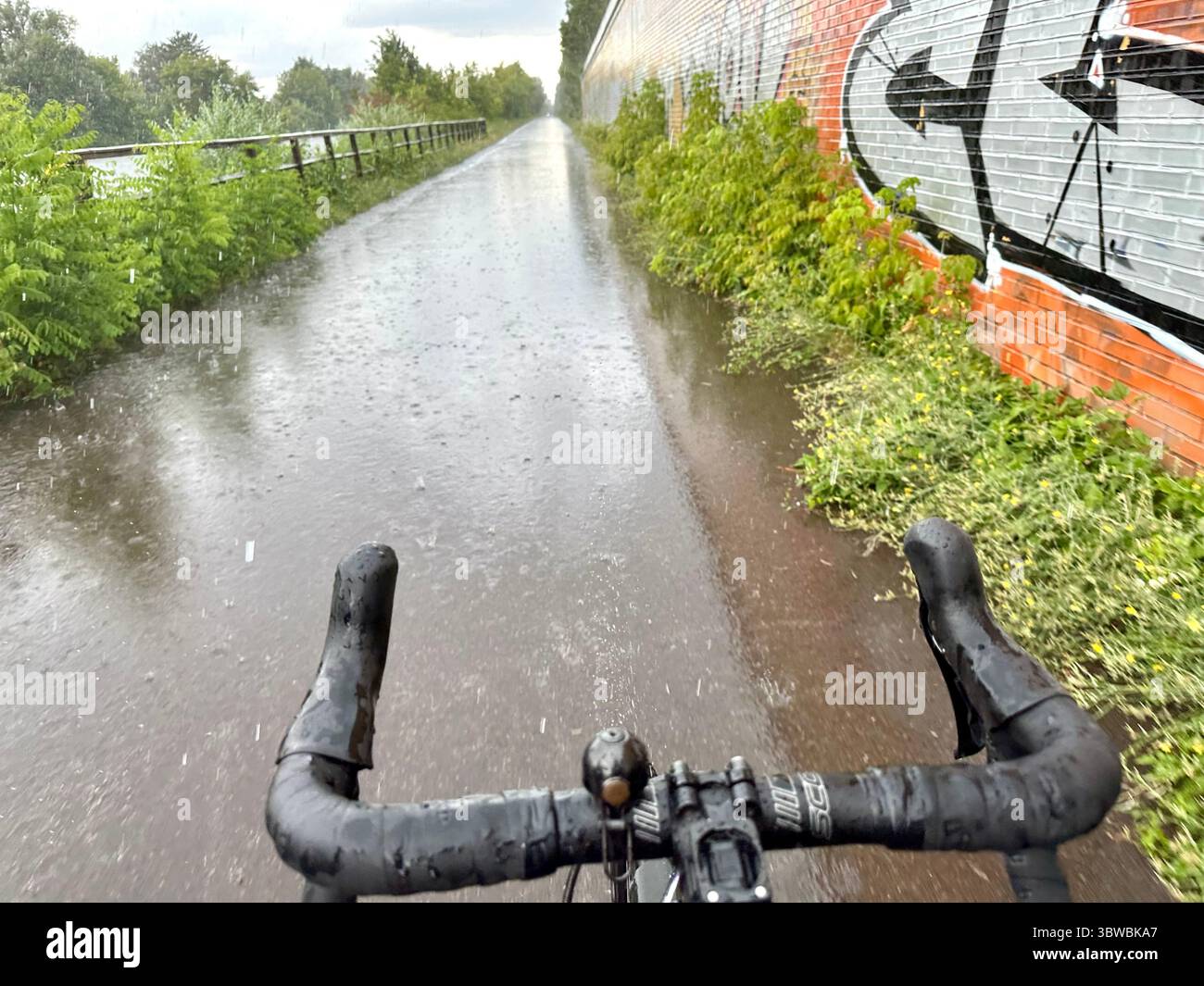 A road seen from the perspective of a cyclist on a bicycle on a rainy day with no hands on the bar - Smartphone Captured Stock Image