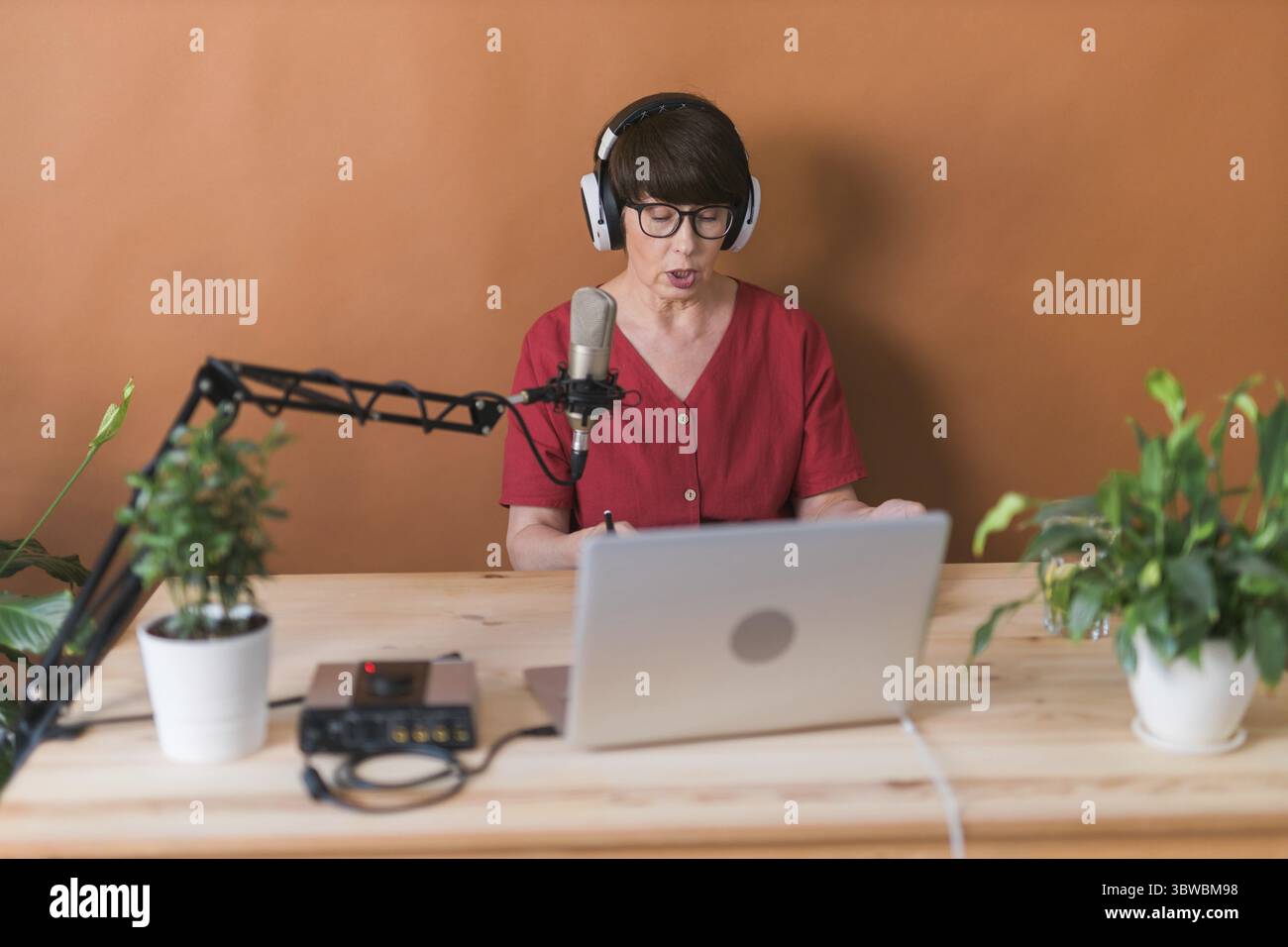 Middle-aged woman radio host making podcast recording for online show - broadcast and dj concept Stock Photo