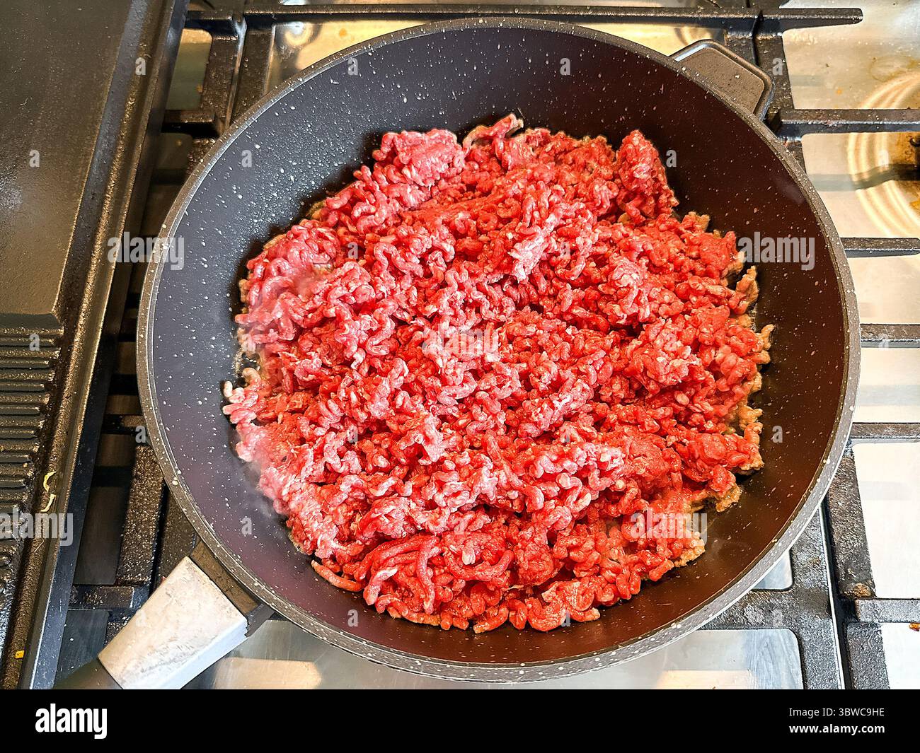 Close up view of a large pan of mince beef on the hob of a cooker. Home cooking concept. - Smartphone Captured Stock Image