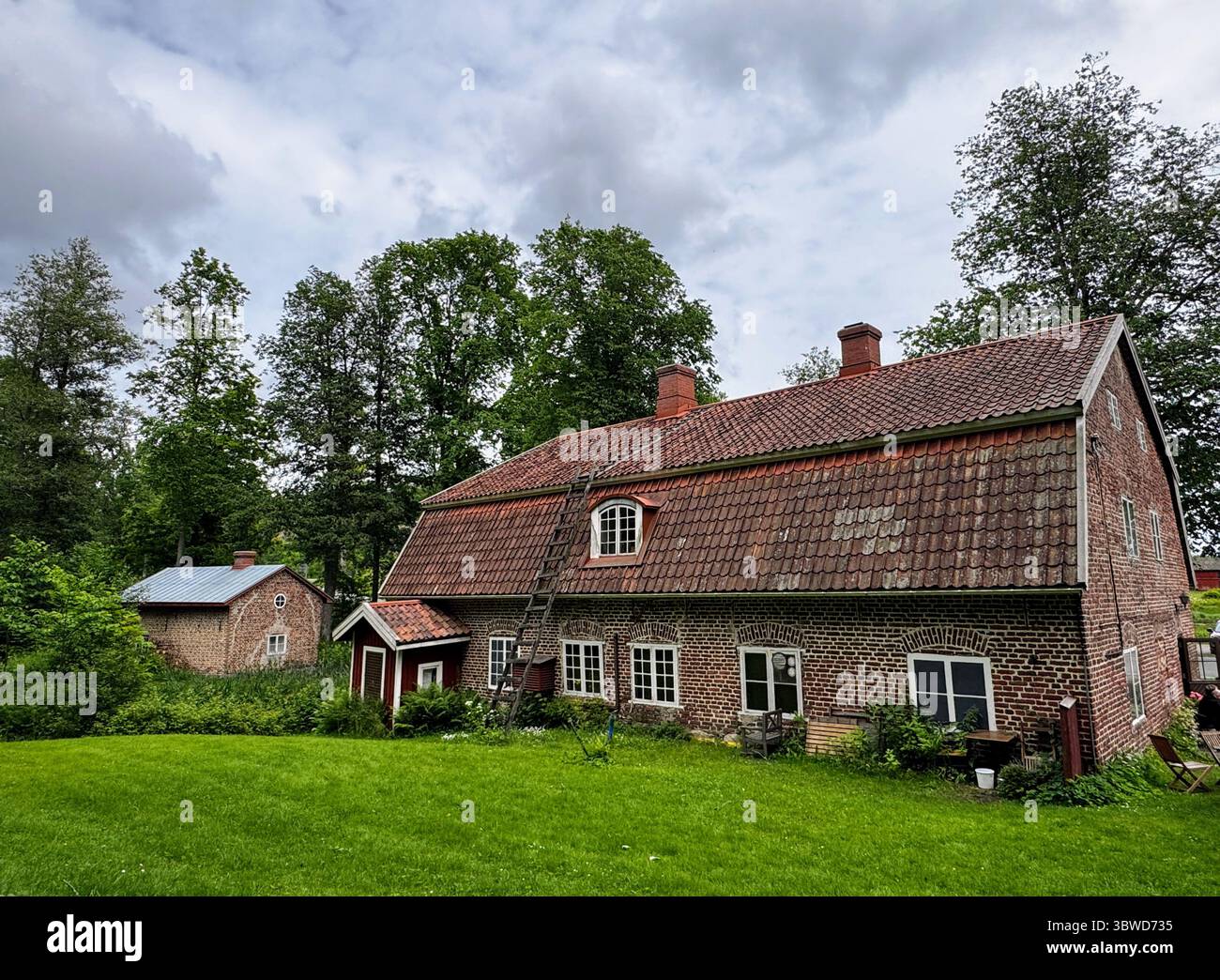 Fagervik Cafe in Old Brick House with Tiled Roof in Green Garden with ladder in historic Fagervik ironworks village, Inkoo, Finland. Rich in heritage - Smartphone Captured Stock Image