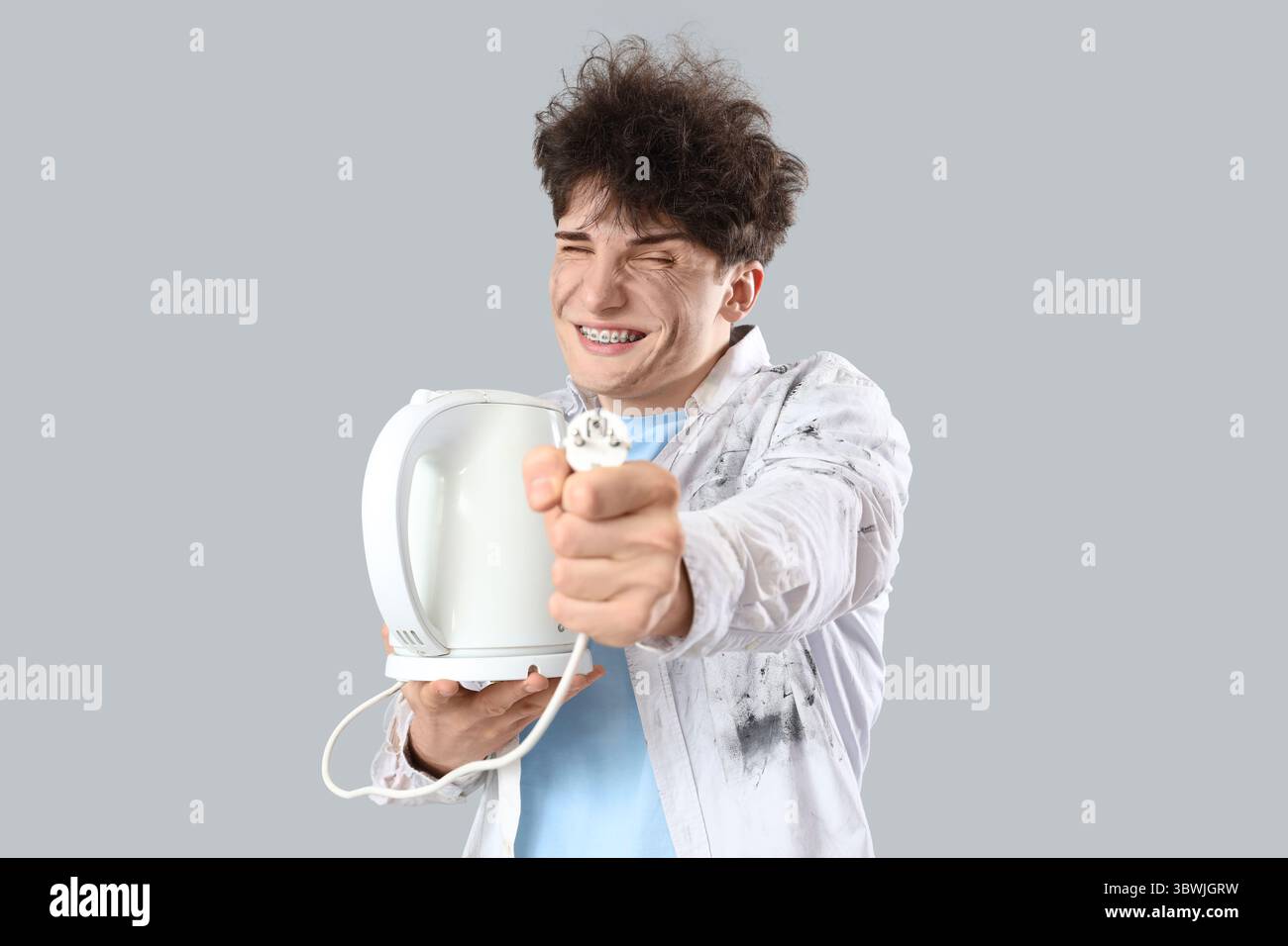 Electrocuted young man with burnt face and electric kettle on light ...