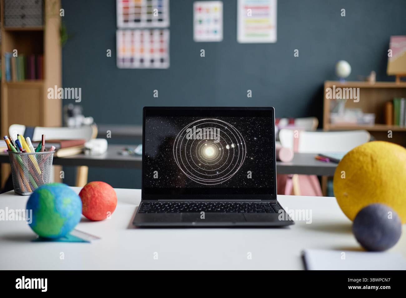 Laptop displaying solar system diagram standing on desk in classroom ...