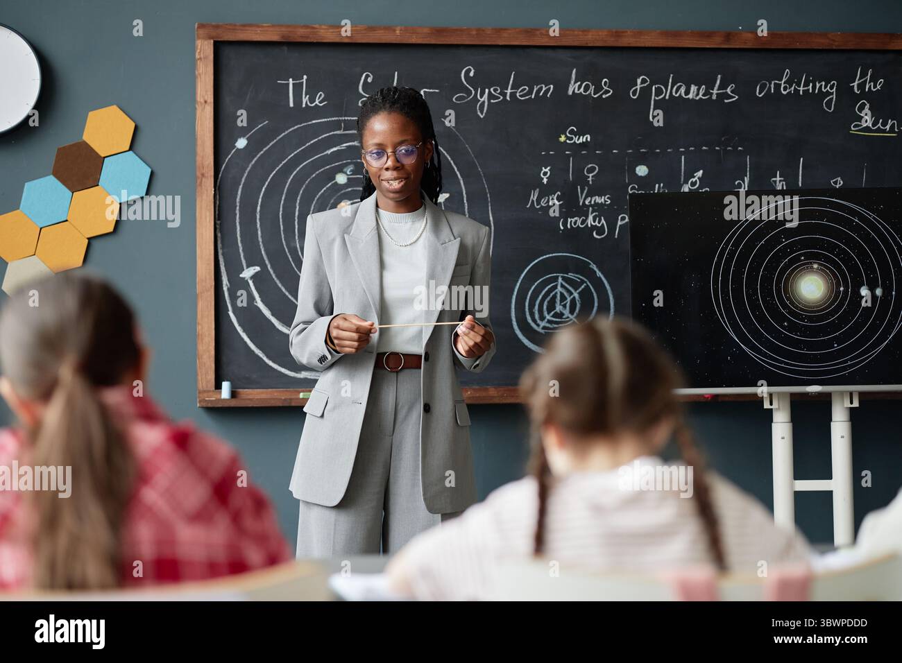 Black woman teacher explaining solar system diagram to group of