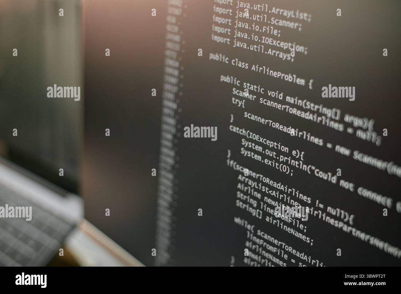 Close up showing computer monitor displaying Java programming code with public class and exception handling visible, focusing on software development and coding process Stock Photo