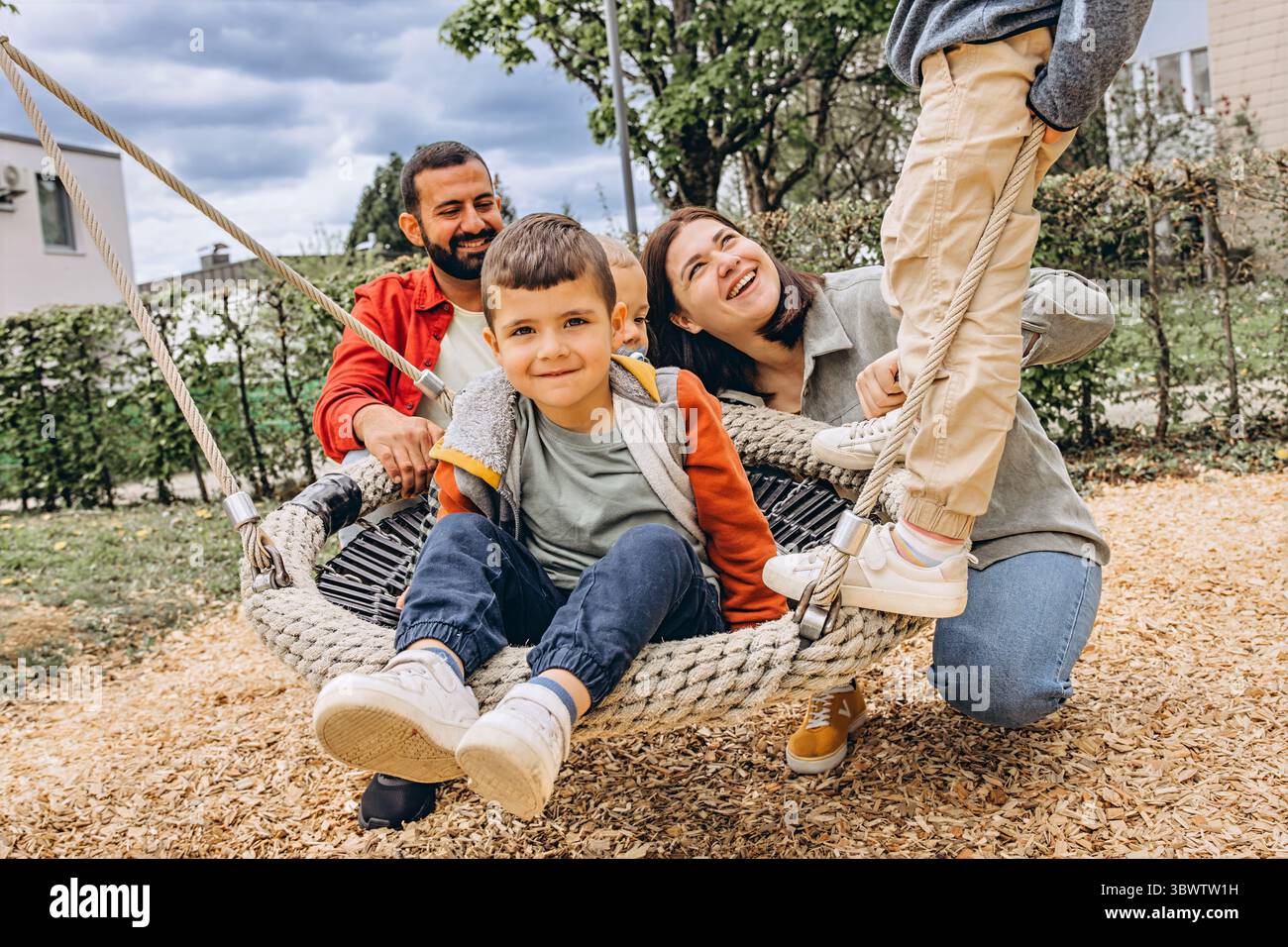 Parent Rope Happy family with two sons playing together on a large rope swing at ...