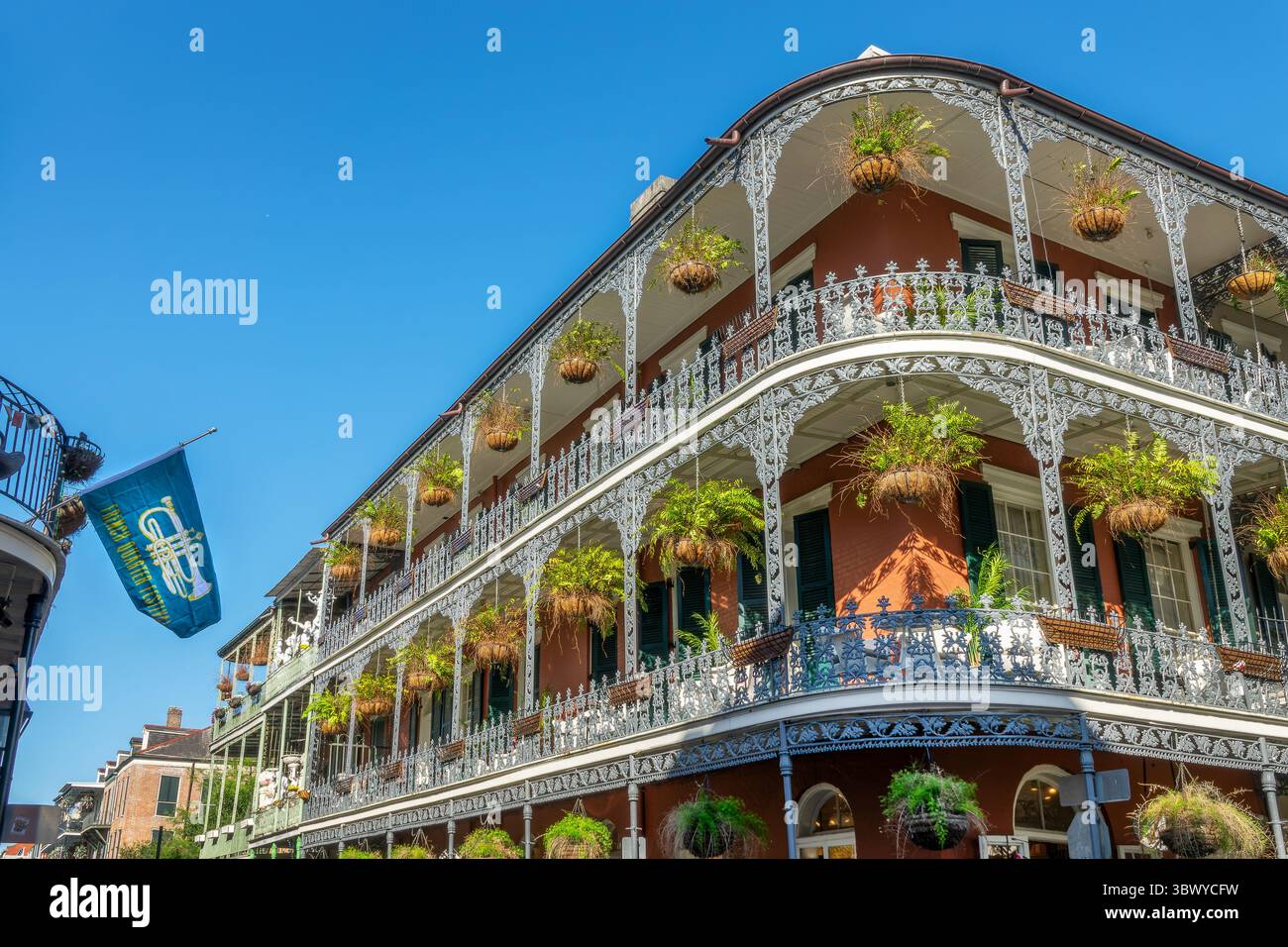 French Quarter Festival flag and NOLA architecture, brick wall building with balconies and intricate ironwork columns, New Orleans, Louisiana Stock Photo