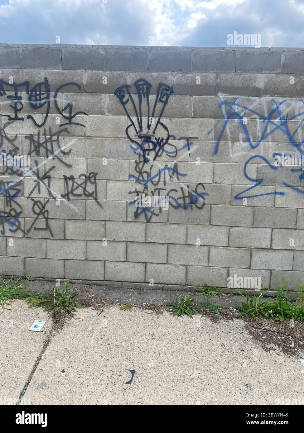 W7M ETGC, a Detroit Crips subset, 3-finger hand-sign tag seen on alley wall over rival tags, "E"; "'T"; "G"; tagged in nails, "3X" tagged on hand - Smartphone Captured Stock Image