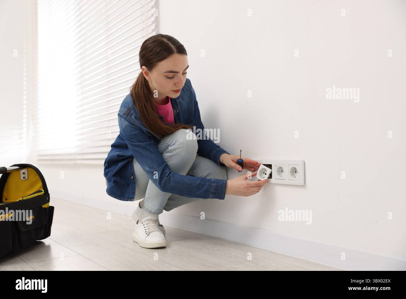 Woman with screwdriver installing new socket at home Stock Photo