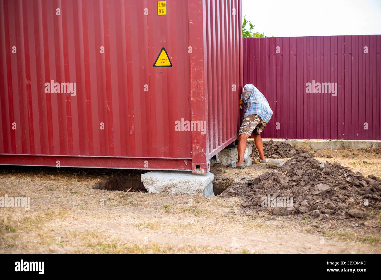 A builder sets up a container on a site reinforced with concrete blocks ...