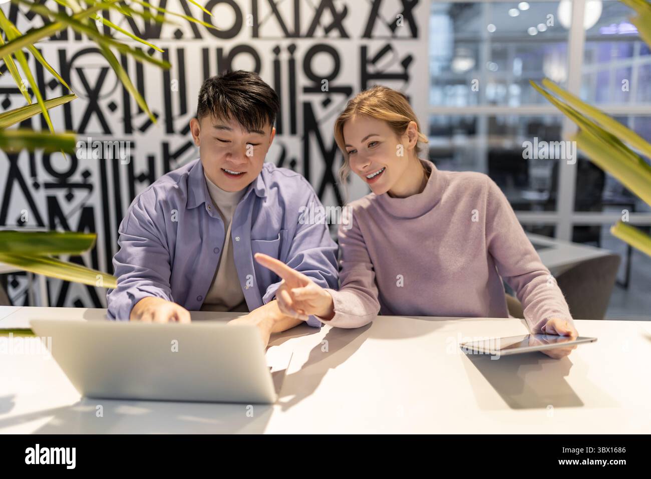 Young people working together on a project and looking involved Stock Photo