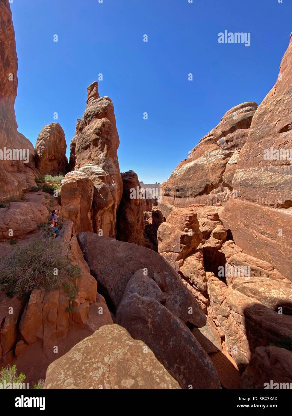 Tourists taking picture of the desert landscape, on the Fiery Furnace Trail, in Arches National park, with sandstone rock formations - Smartphone Captured Stock Image
