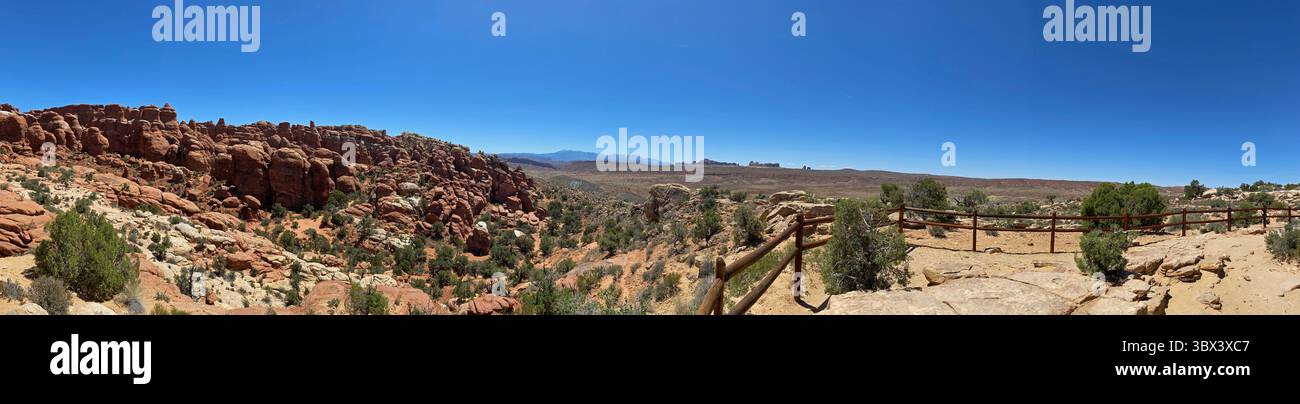 Desert landscape of the Fiery Furnace viewing area in Arches National Park, with sandstone rock formations, fins, hoodoos and Creosote bushes and a wo - Smartphone Captured Stock Image