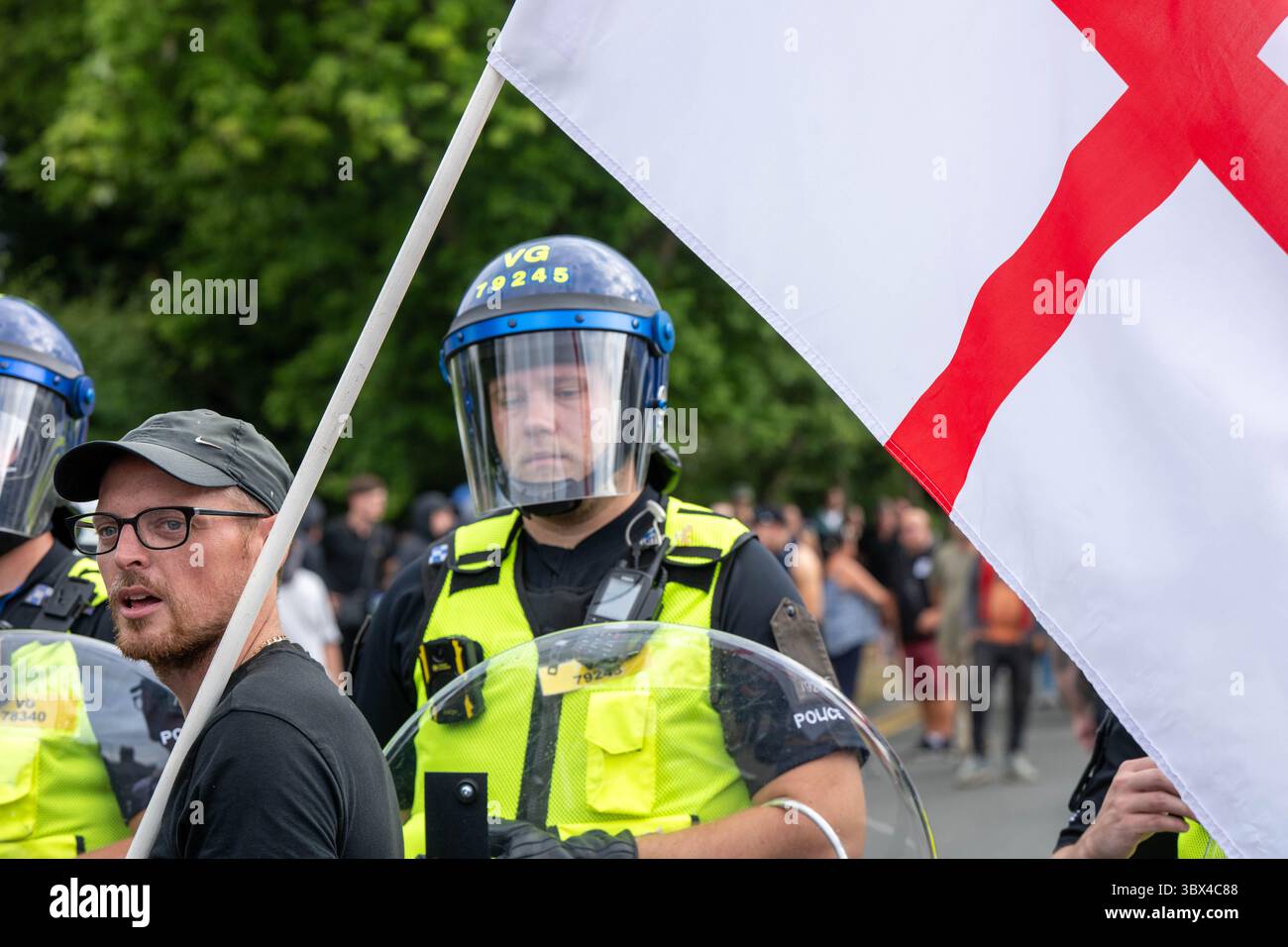 Epping Essex 17 Jul 2025 A small group of pro immigrant protesters were trapped in the middle of Epping by locals and anti immigrant protesters. The pro immigrant protesters were protected by Essex Police, some in riot gear with shields. St George’s flag Credit: Ian Davidson/Alamy Live News Stock Photo
