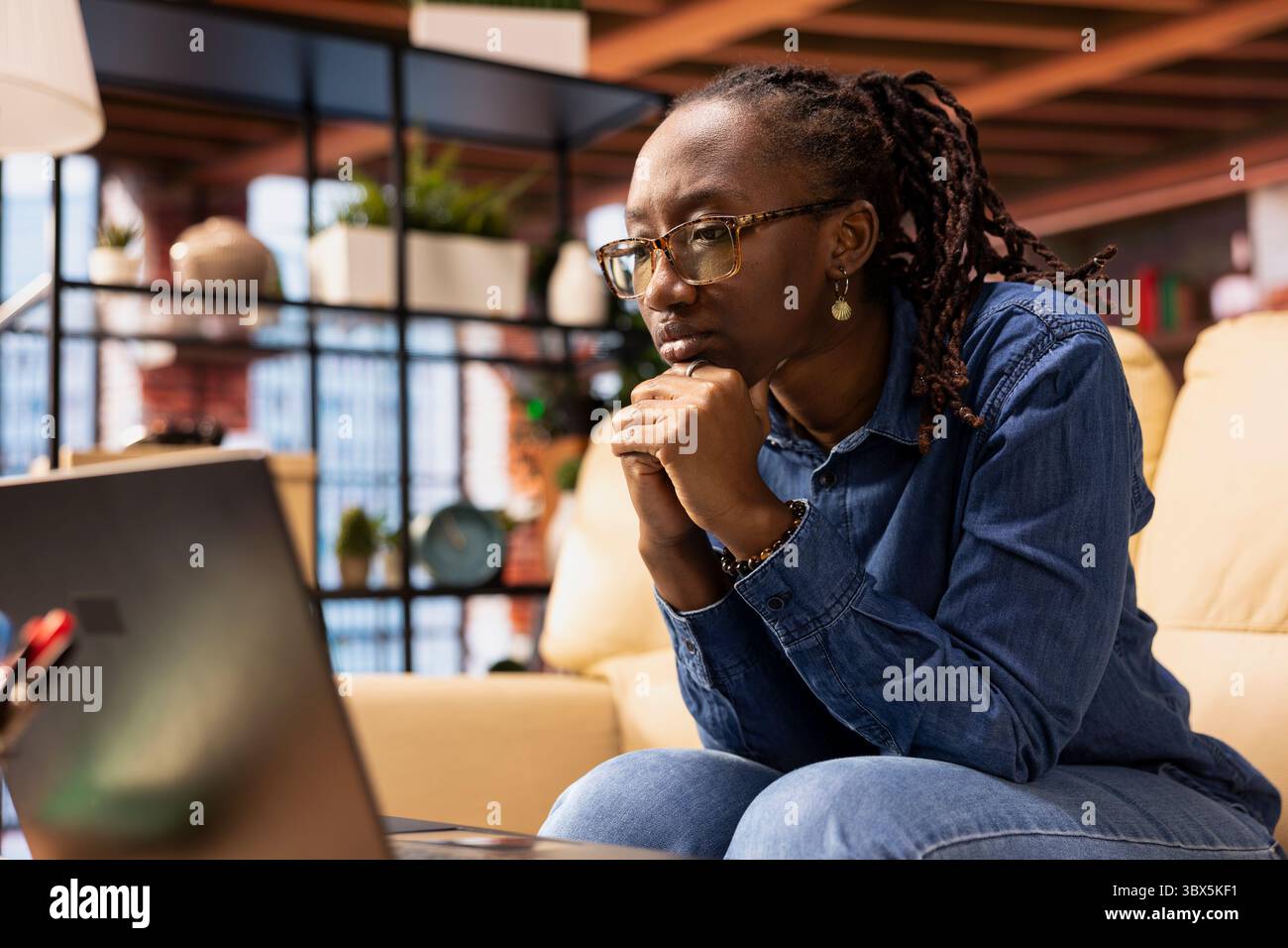Independent woman using laptop for remote job tasks at home office, doing research and enjoying the benefits of schedule flexibility. Embracing the modern lifestyle of freelance work. Stock Photo
