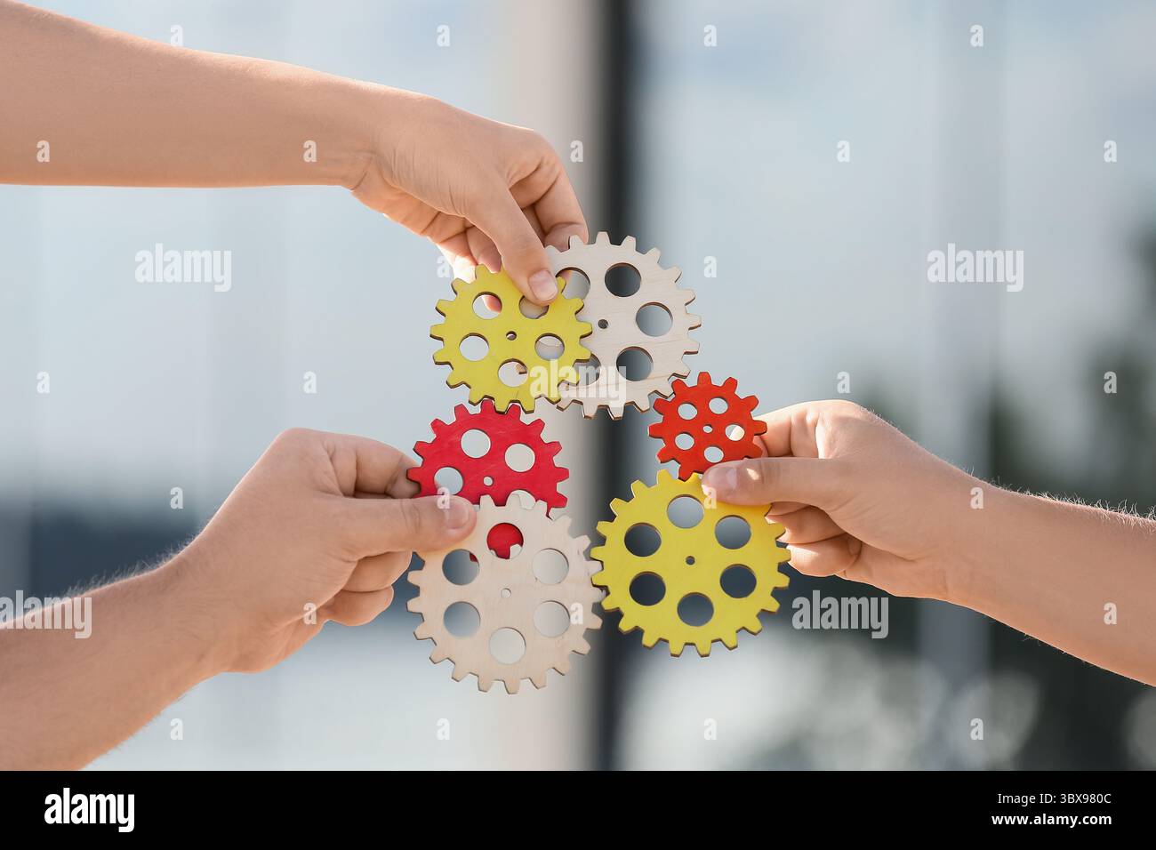 Many hands with gears outdoors Stock Photo