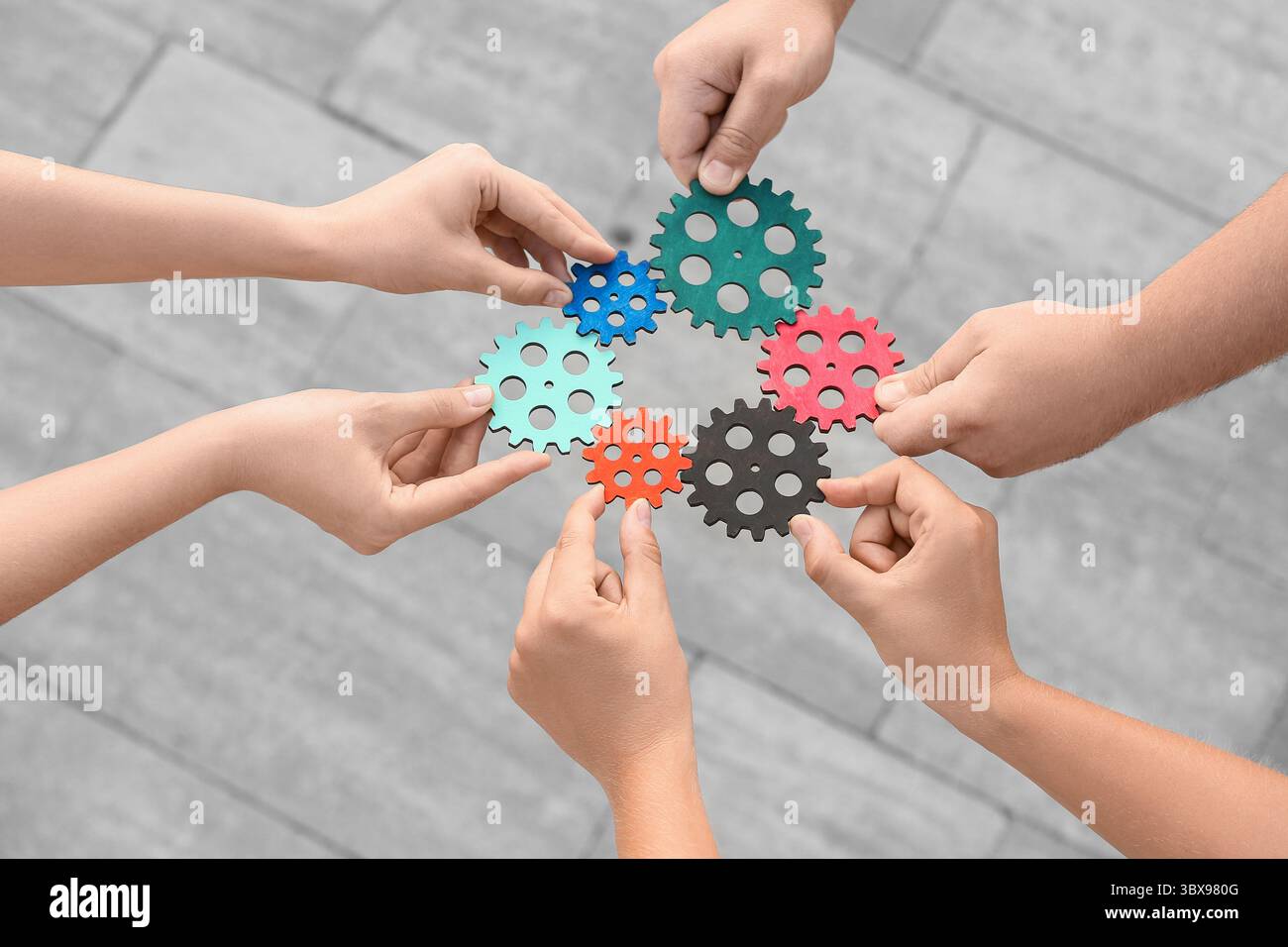 Many hands with gears outdoors Stock Photo