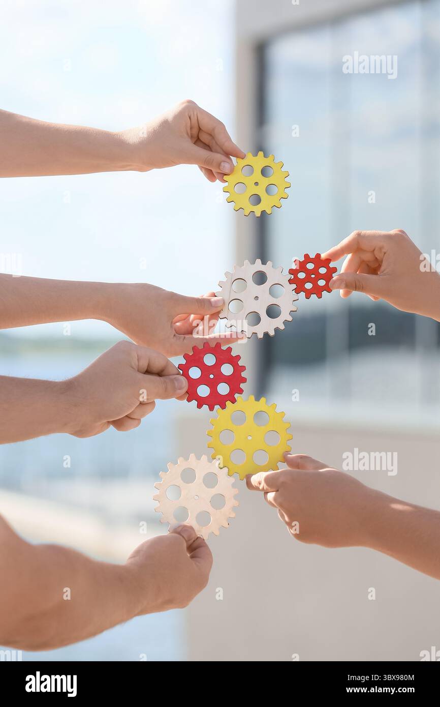 Many hands with gears outdoors Stock Photo
