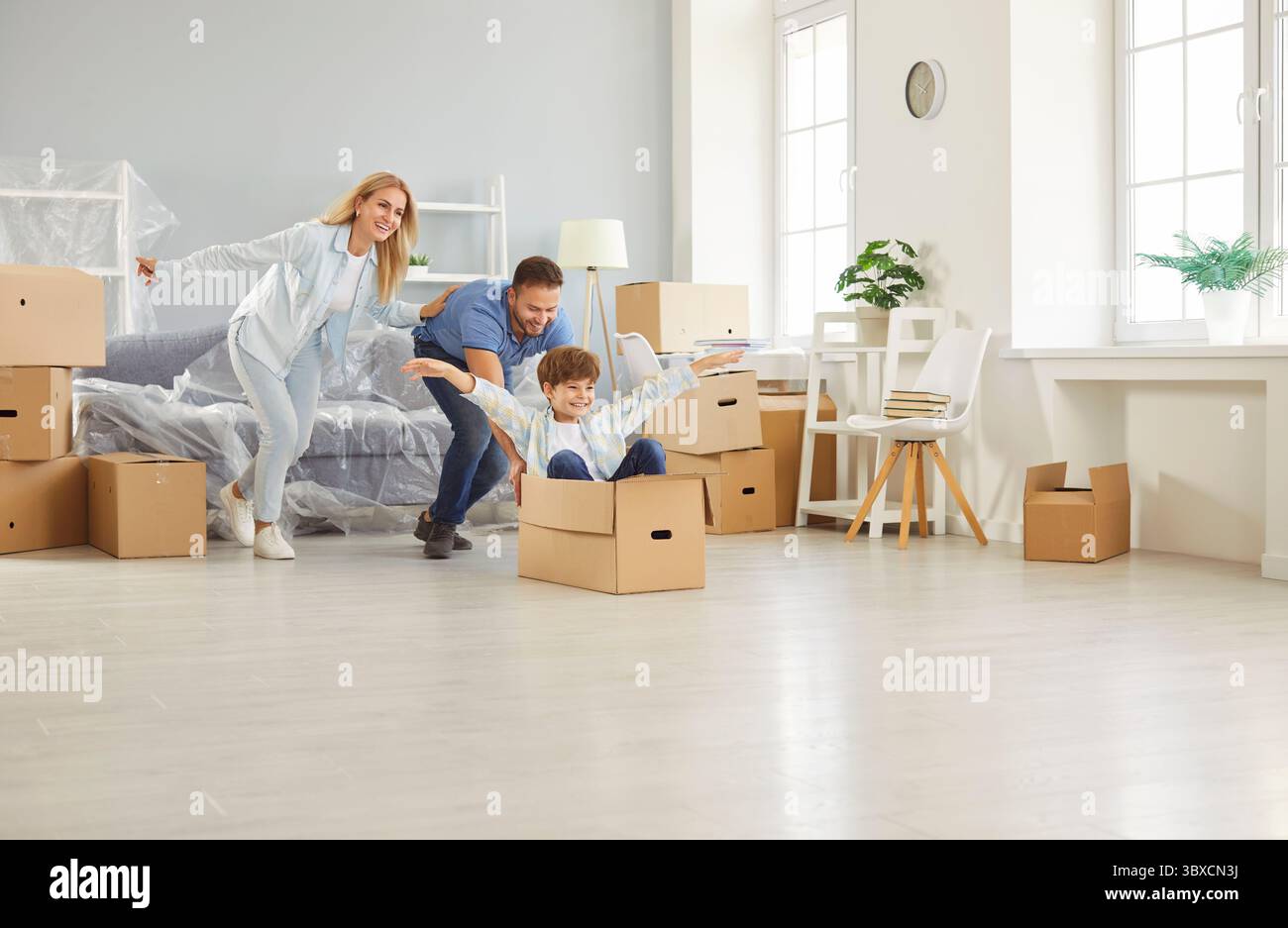 Happy family, cheerful owners cardboard boxes playing moving new flat, enter home, excited parents Stock Photo