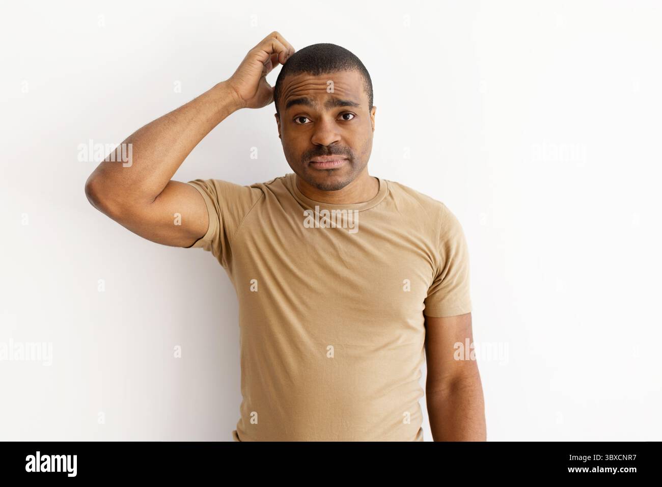 Confused black man scratching his head with uncertain expression Stock Photo