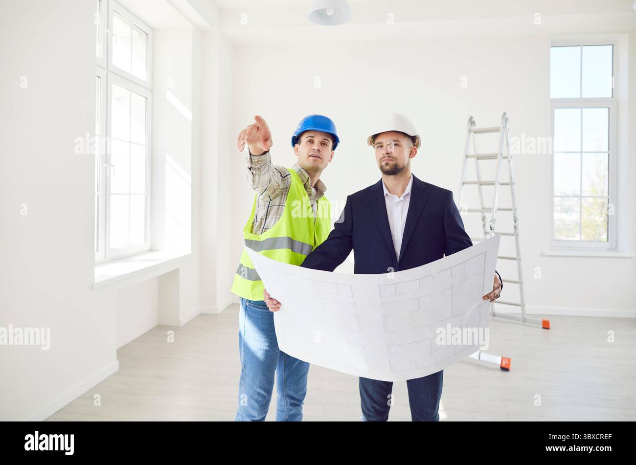 Builder Discussing Construction Plan With Customer At Site Stock Photo
