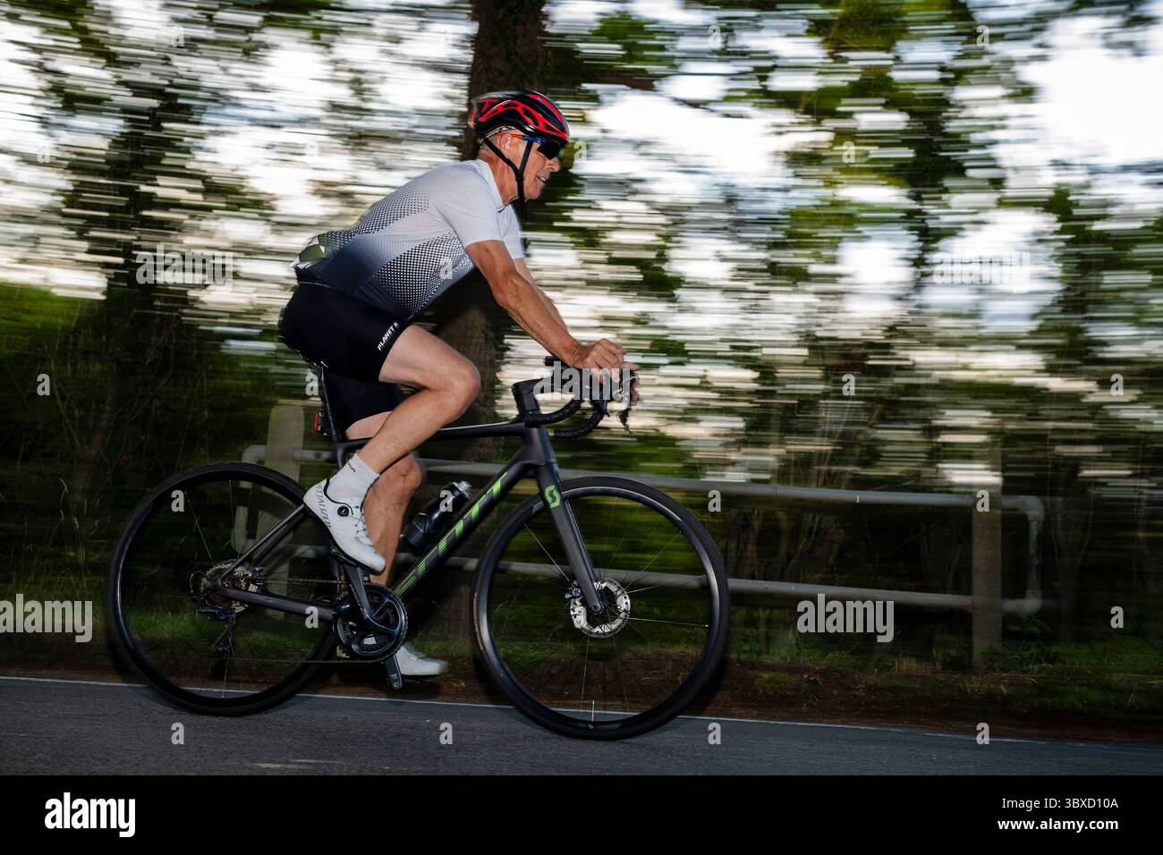 Cyclist in his 60s motion, blur focused on the country road in southern England Stock Photo