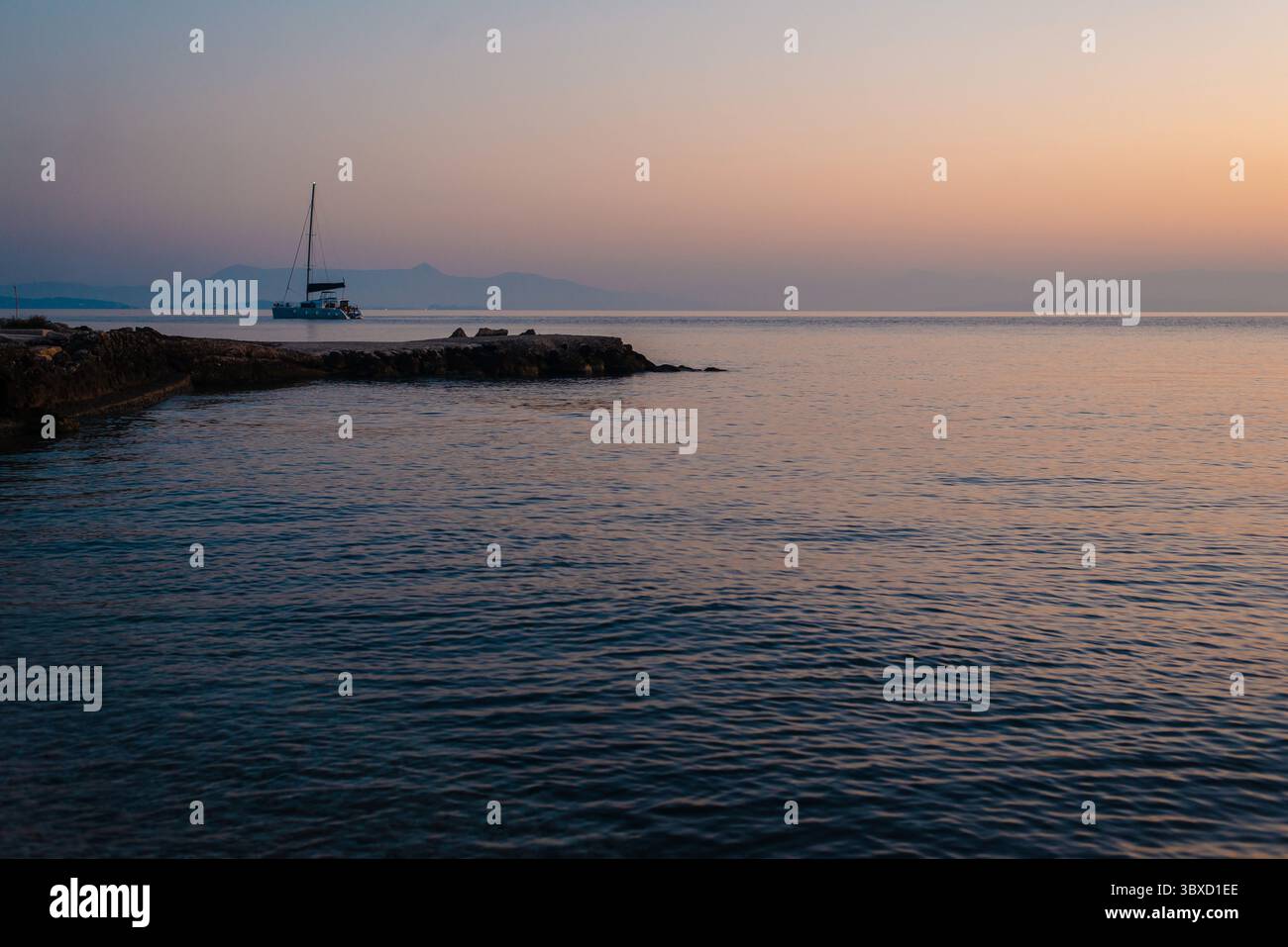 Serene Sunset Over Calm Sea with Sailboat Stock Photo