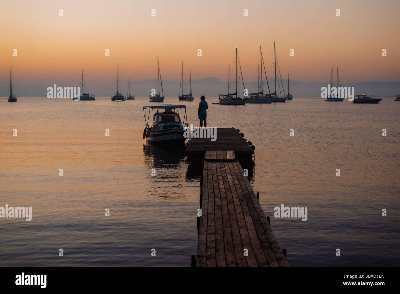 Serene Sunset Over Sailboats and Pier Stock Photo