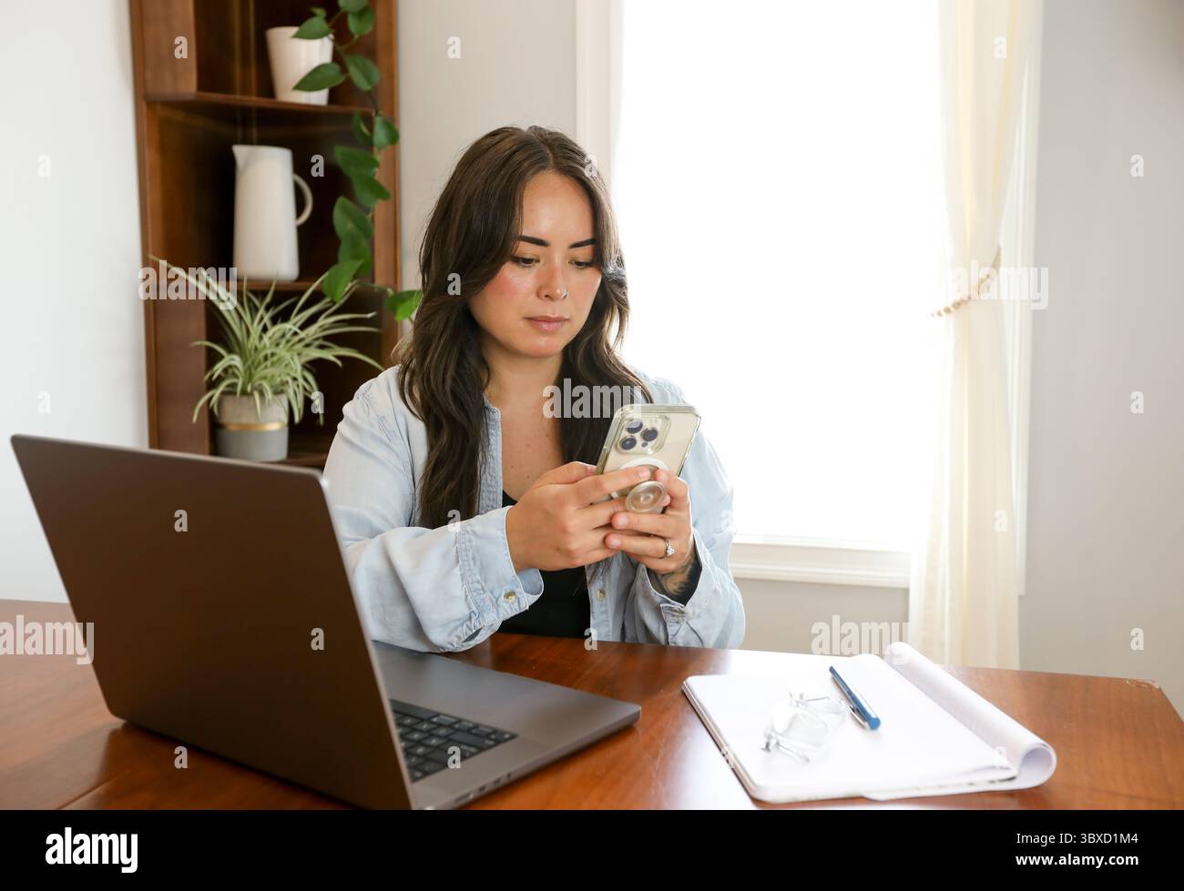 Woman working from home on phone with pop socket Stock Photo