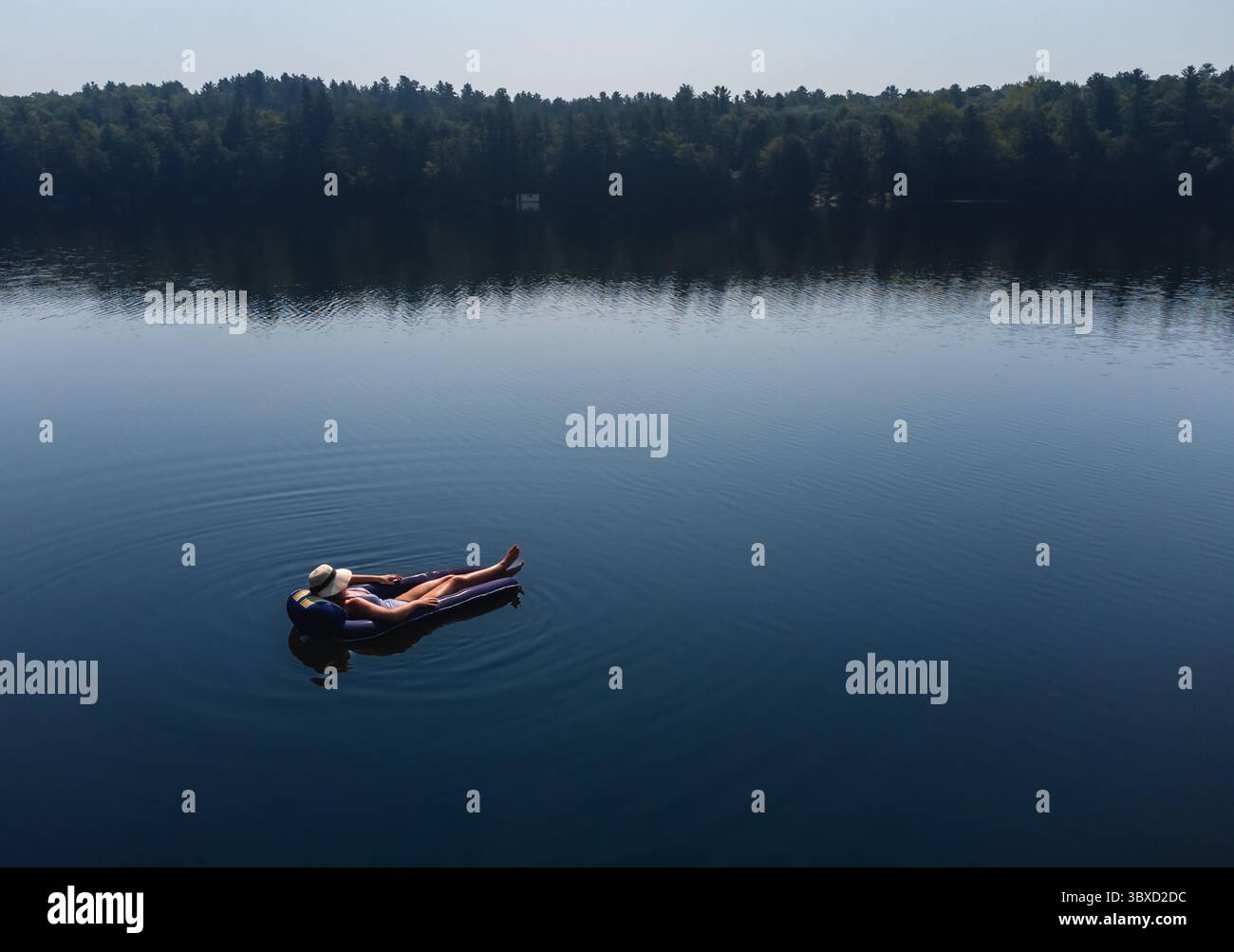 Aerial view woman floating on lake in inflatable chair in summer. Stock Photo