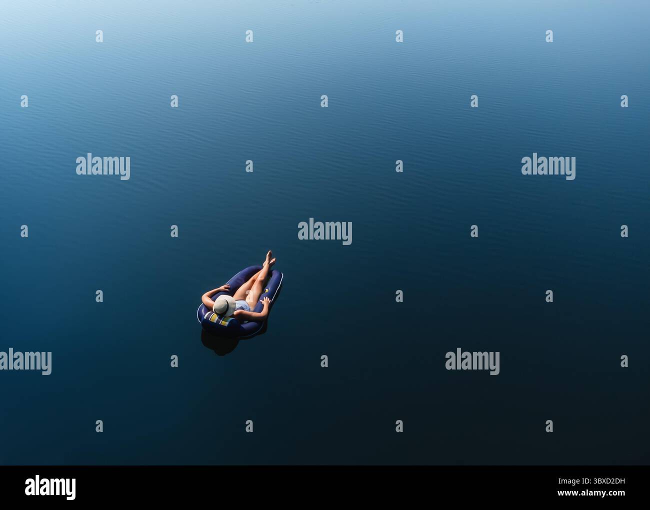 Aerial view woman floating on lake in inflatable chair in summer. Stock Photo