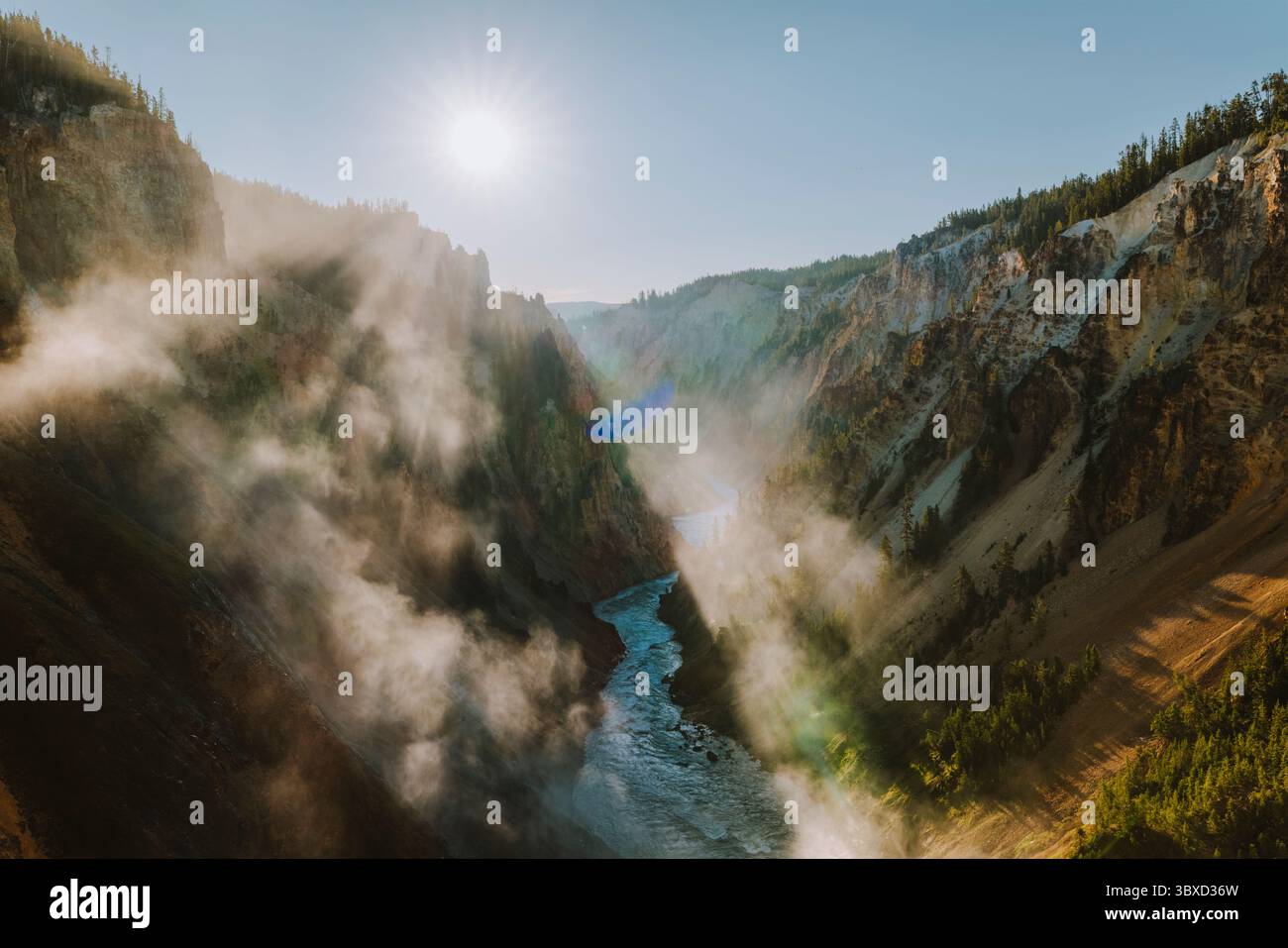 Sunlight breaks through clouds over mist-filled canyon walls Stock Photo