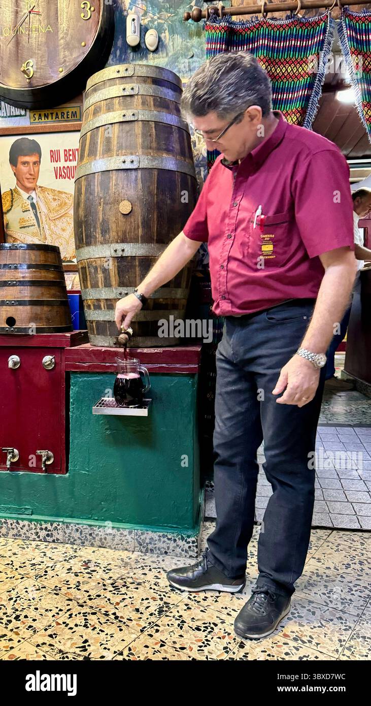 Sever pouring red wine from a barrel at tavern Taberna do Quinzena Santarem Portugal - Smartphone Captured Stock Image