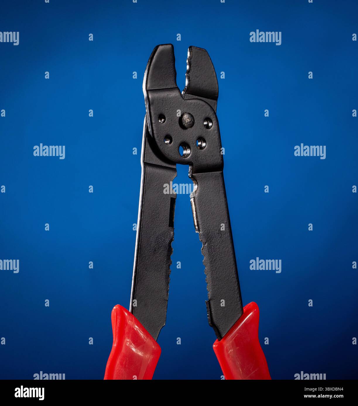 Professional electrical cable crimping pliers displayed on a vibrant blue gradient background, showcasing precision tools for electrical projects. Ide Stock Photo