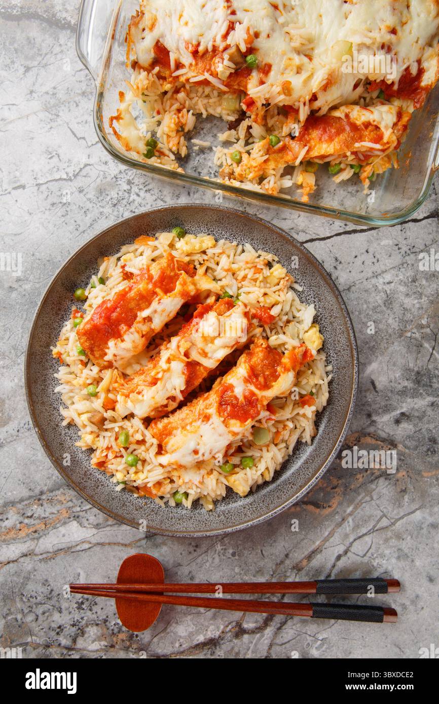 Baked Pork Chop Rice is a delicious casserole öøåð egg fried rice, pork chops and a tomato gravy topped with melted cheese closeup in a plate on the t Stock Photo
