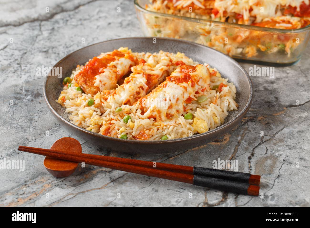 Baked Pork Chop Rice is a Hong Kong classic dish egg fried rice, seared pork and a rich tomato sauce rest under cheese closeup in a plate on the table Stock Photo