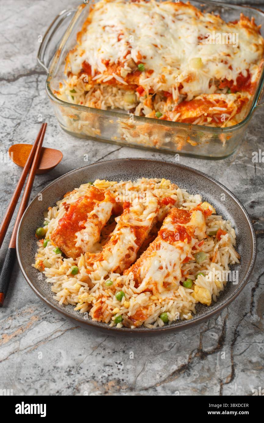 Baked Pork Chop Rice is a delicious casserole öøåð egg fried rice, pork chops and a tomato gravy topped with melted cheese closeup in a plate on the t Stock Photo