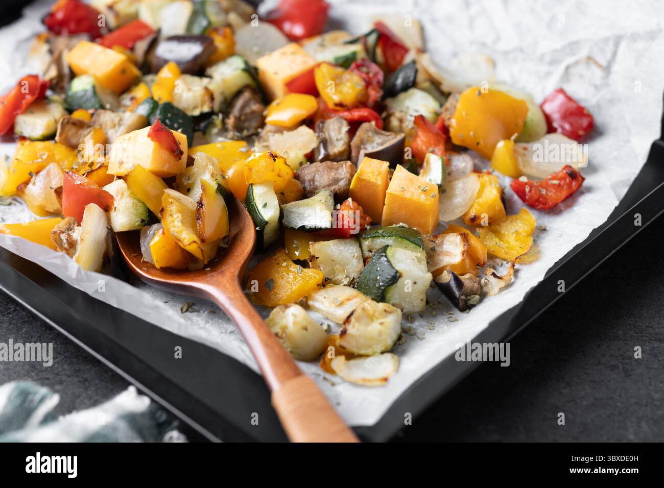 Roasted vegetables on a baking tray on black background Stock Photo
