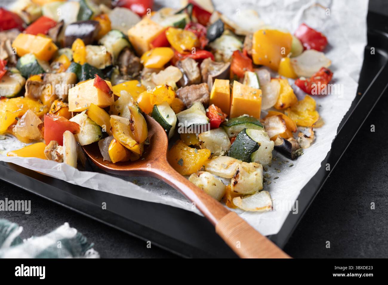 Roasted vegetables on a baking tray on black background Stock Photo