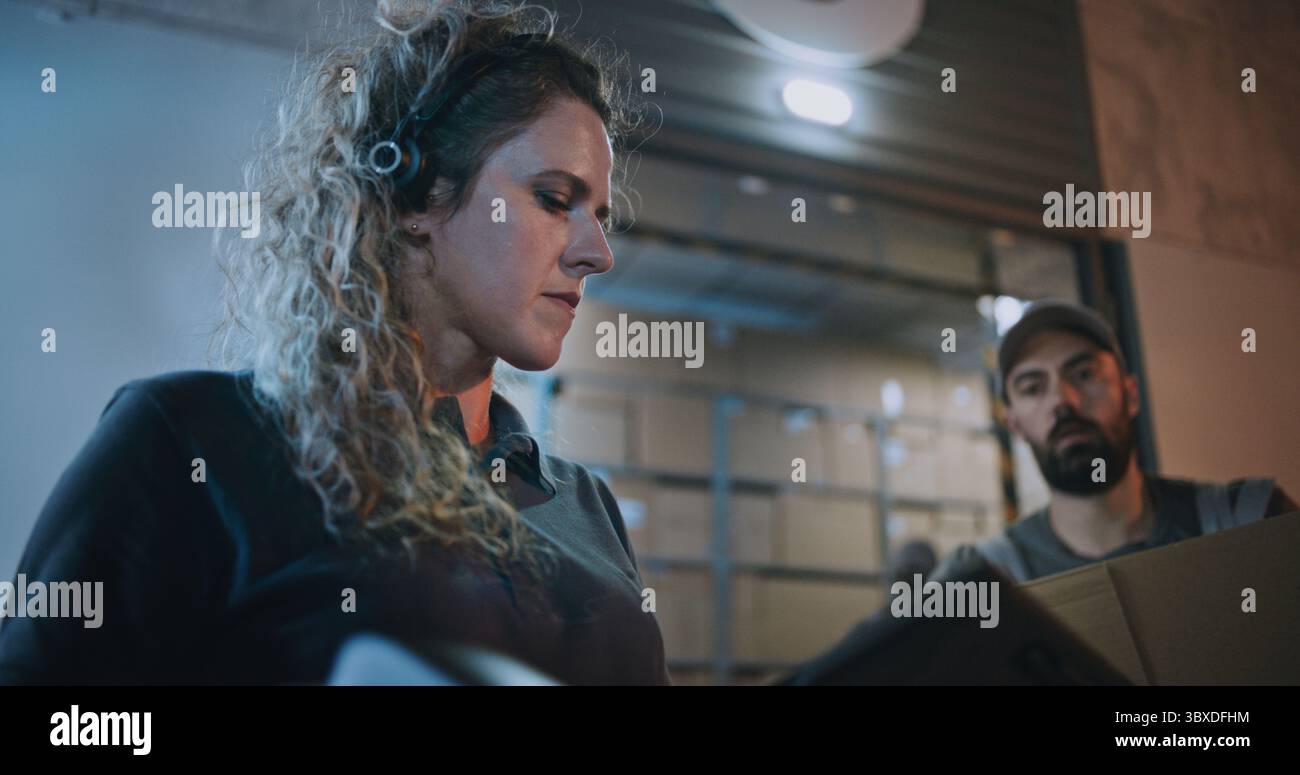 Female Manager Scanning Cardboard Boxes with Scanner, Using Tablet Computer, Working at Night. Multiethnic Workers Carrying Parcels with Online Orders, Goods from Logistics Warehouse. Slow Motion. Stock Photo