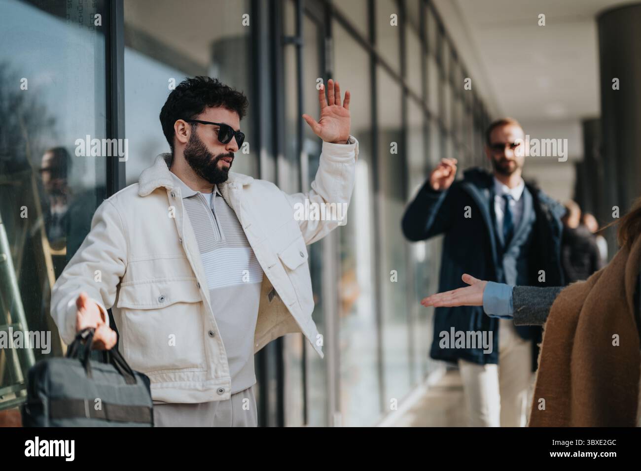 Two stylish men greeting each other outdoors on a sunny day Stock Photo