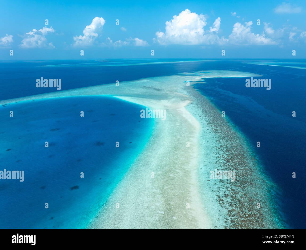 Aerial view of turquoise shallows meet deep blue ocean under a sky ...