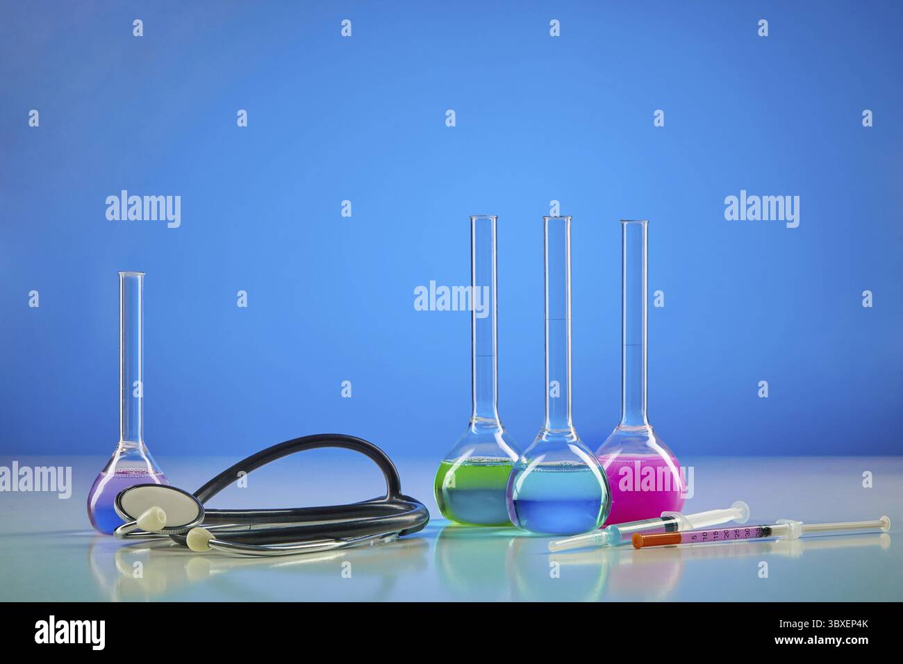 Four medical flasks with colorful chemical reagents. Testing kit, syringe and phonendoscope, blue background. Laboratory research Coronavirus. Worldwi Stock Photo