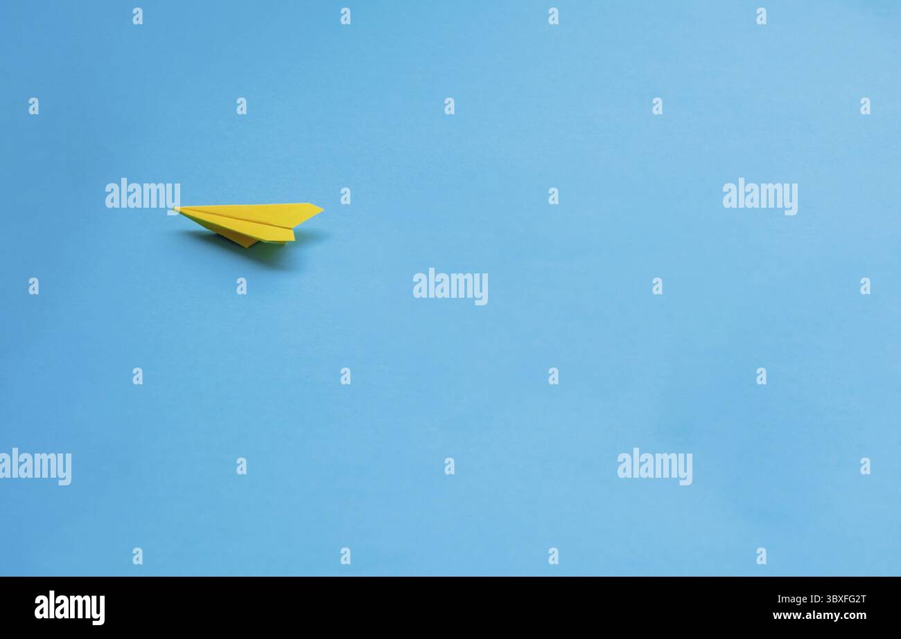Yellow paper airplane on blue background Stock Photo