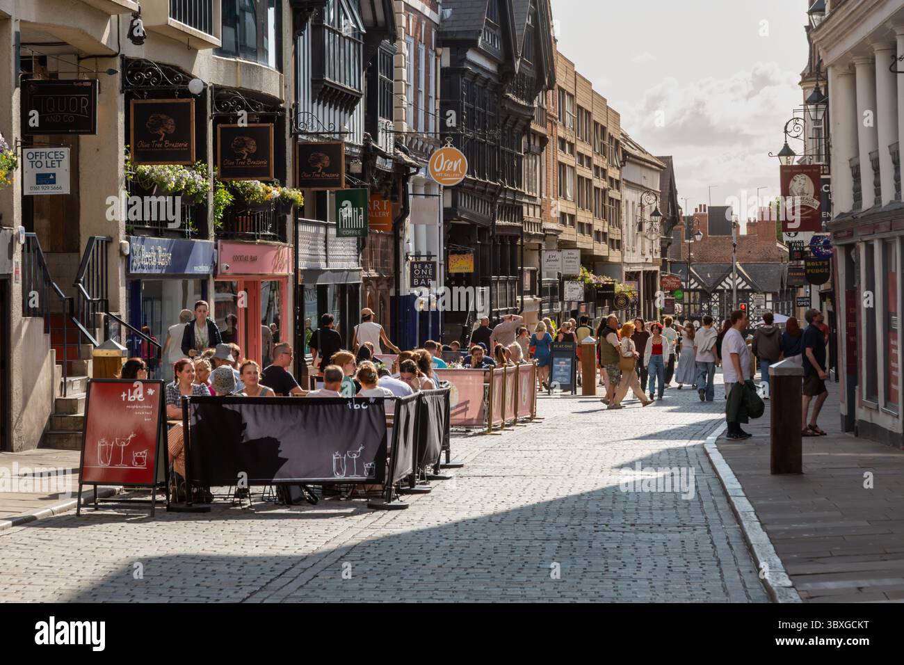 People dining and drinking seated on the street, Bridge Street Chester, Cheshire, UK. 2025 Stock Photo