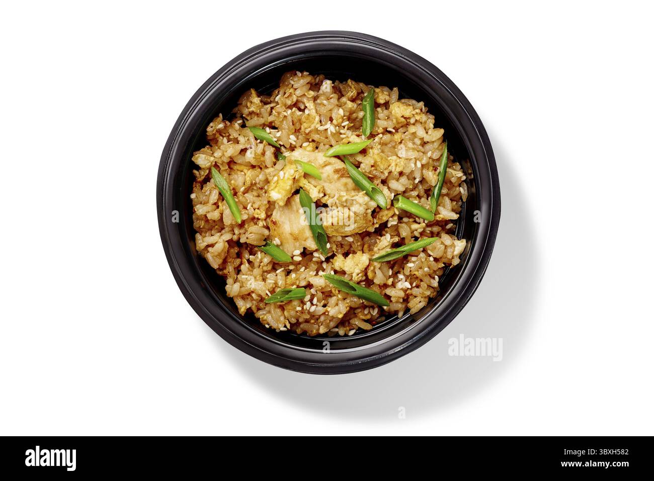 Overhead view of a tasty portion of chicken fried rice seasoned with sesame seeds and green onions, served in a black bowl Stock Photo