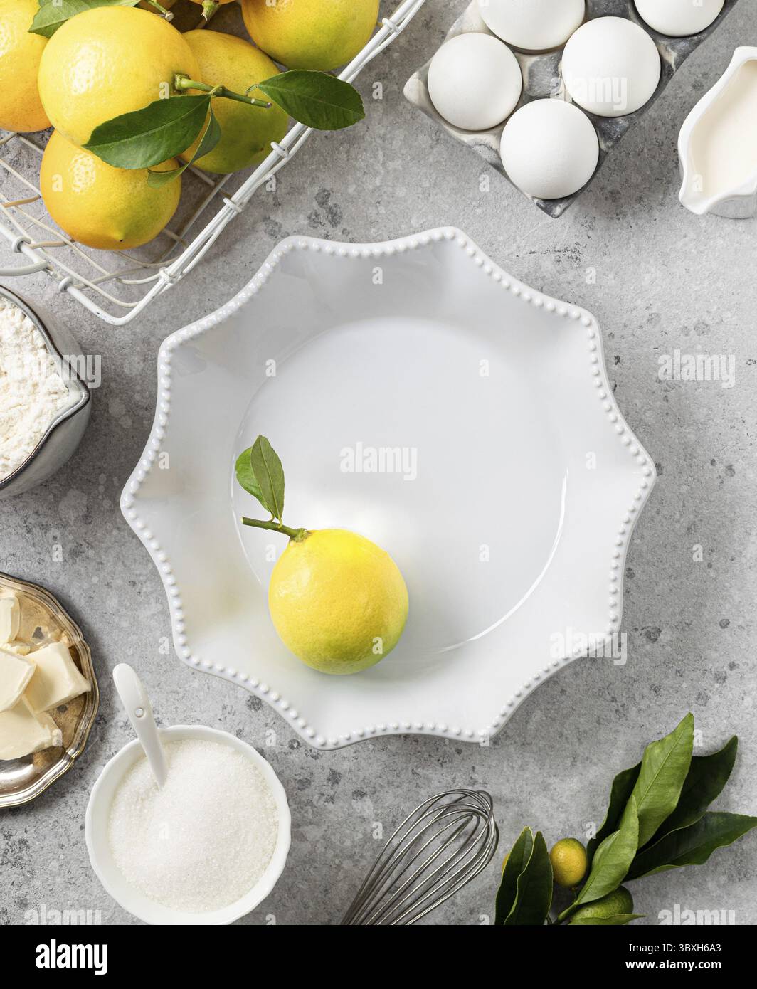Food, White ceramic cake pan with lemons. Ingredients for making a lemon curd pie on a white stone table Stock Photo