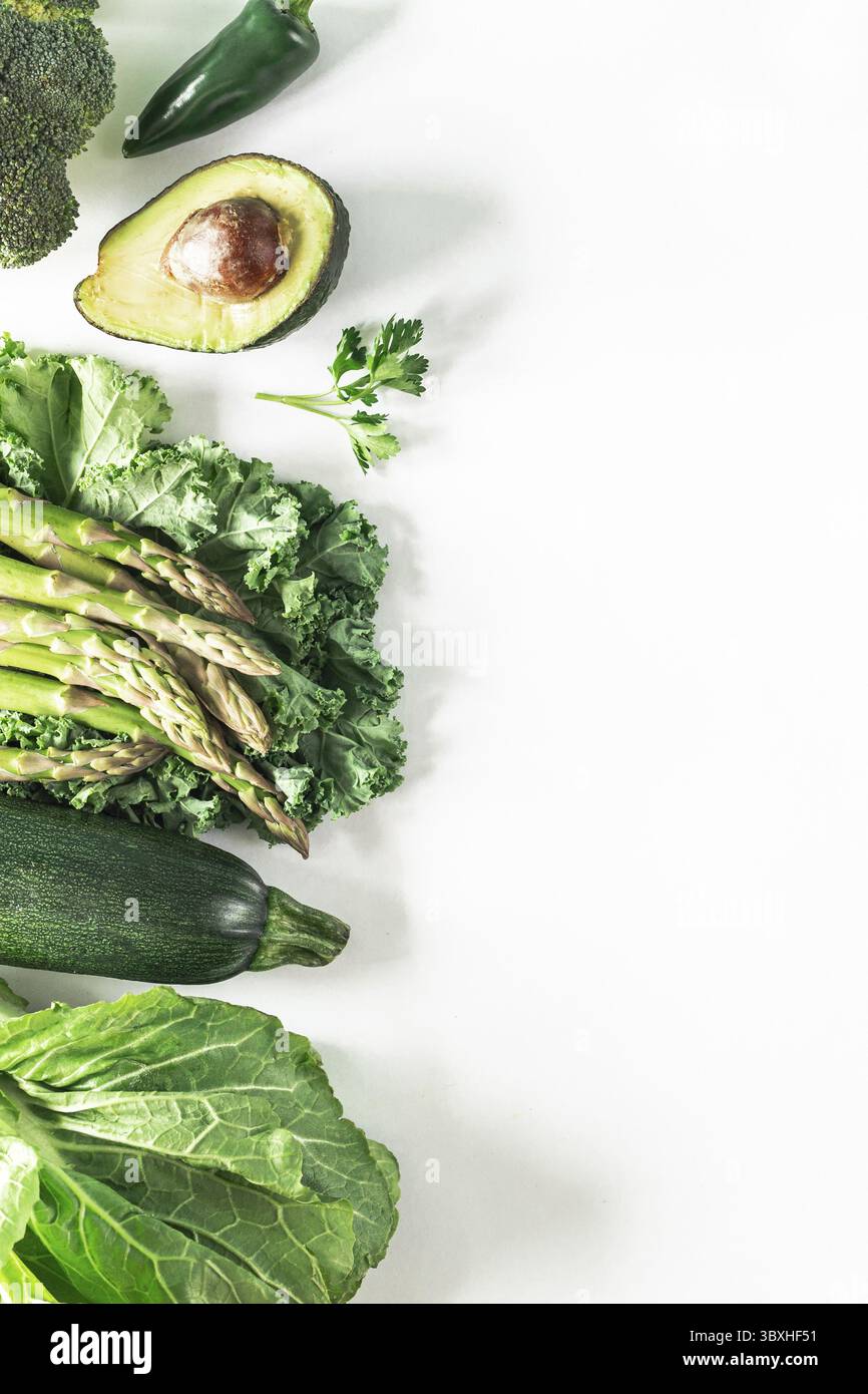 Food, Various fresh green vegetables on a white background: broccoli, celery, avocado, zucchini, kale, parsley, hot pepper, lettuce leaves. Healthy ve Stock Photo