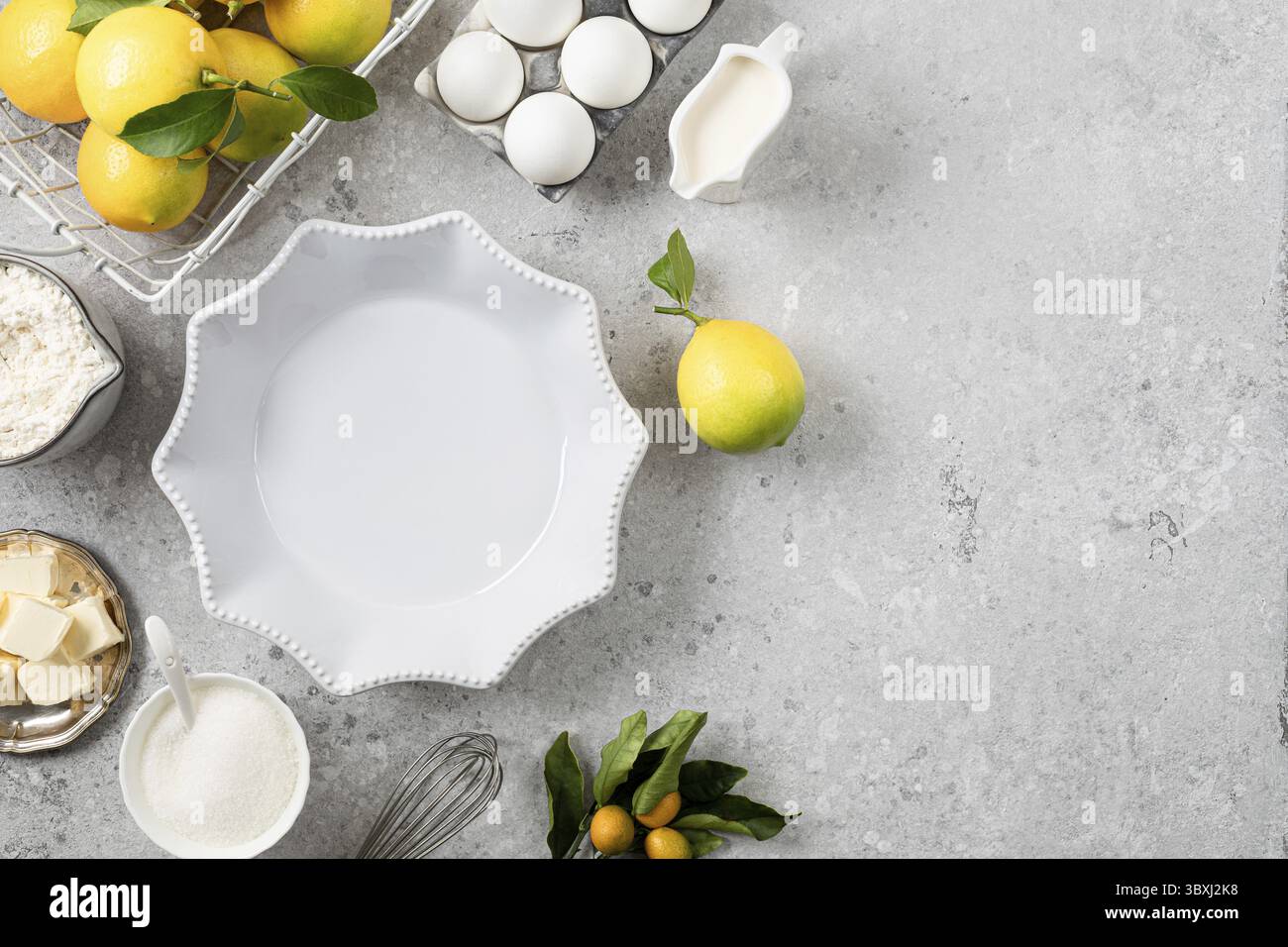 Food, White ceramic cake pan with lemons. Ingredients for making a lemon curd pie on a white stone table Stock Photo