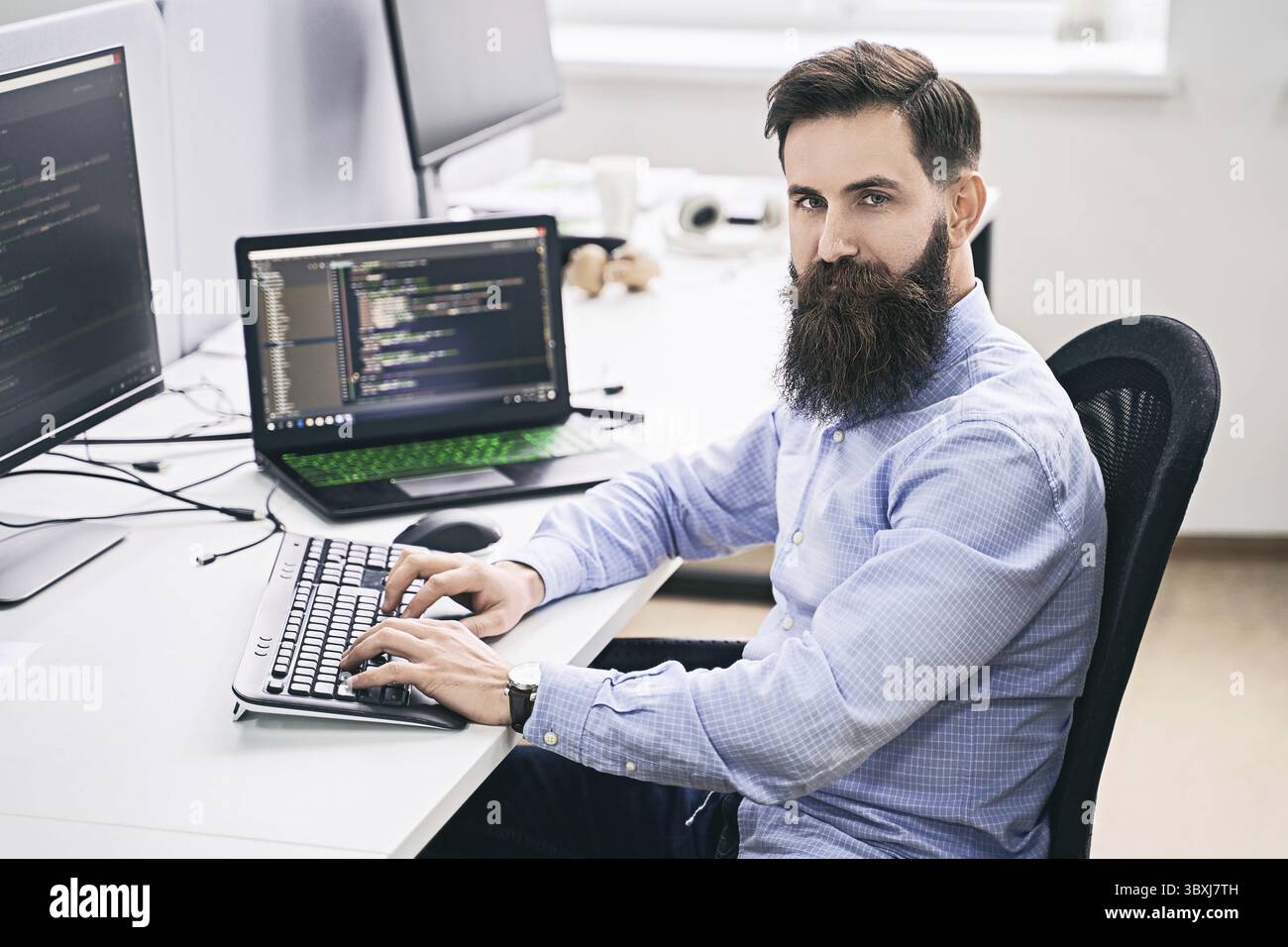 Senior developer working on computer in IT office, sitting at desk and coding, working on a project in software development company or technology star Stock Photo