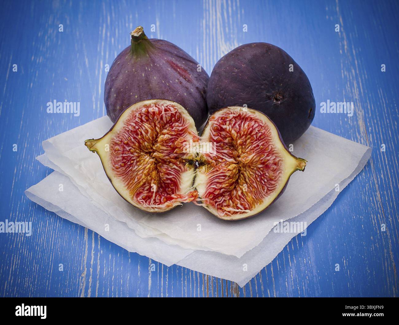 Three ripe figs on baking paper background, close up Stock Photo